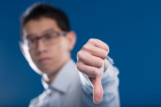 Asian man, out of focus, disagrees and shows it with a clear thumbs down in the foreground