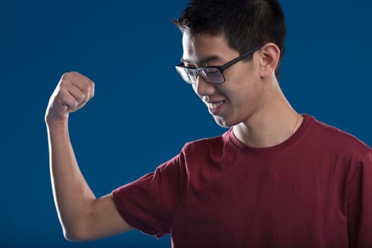 An East Asian man, with glasses, expresses joy by raising his arm, celebrating success. Overcame adversity with fortune and effort. Portrait of positive future and immense satisfaction