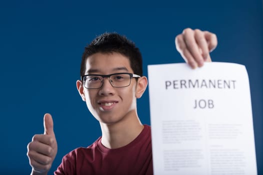 Young man thumbs up, shows off his permanent job contract! No more precarious jobs, he can now make long-term plans. Finally, he can start a family and buy a home