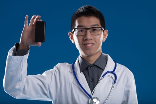 Asian medic showcases a digital device, endorsing telemedicine. Supports remote healthcare, sidestepping high costs. Long live innovation