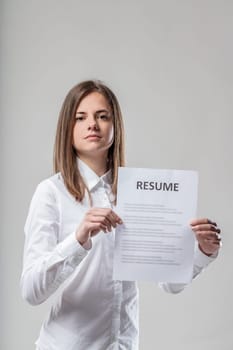 Woman with upright stance shows curriculum job offer or candidate's reply. Describing skills is a skill. White shirt, brown medium-length hair