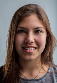 Vertical portrait of the face of a young girl with light eyes and long brown hair she is Western but may have relatives of Asian descent