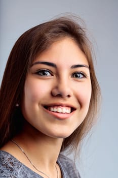 Portrait captures a youthful female with an engaging smile, brown eyes, and casual wear