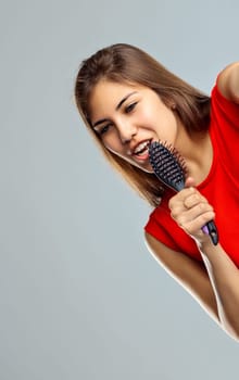 Woman playfully sings into a hairbrush, pretending its a microphone in a moment of joy