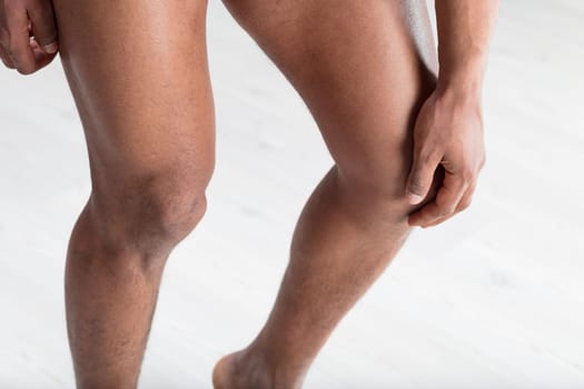 Man's hand rests on his knee, checking joint health and muscle tone. Fitness brings youthfulness