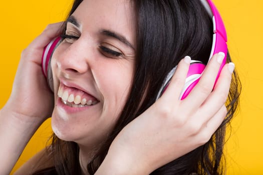A vibrant woman laughs and sings, savouring sound from pink headphones. Captivated by storytelling, instruments