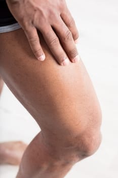 Hand of a black person resting on the thigh of a discreetly muscular leg. and toned. Keeping fit and healthy by taking care of your skin and exercising is good for you and keeps you young longer