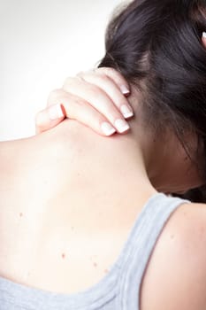 Woman massages neck's base above her back, troubled by cervical pain. Exercise and analgesics help headaches