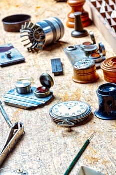 Amidst horology's chaos, a dismembered watch case lies, the silent heart of time paused