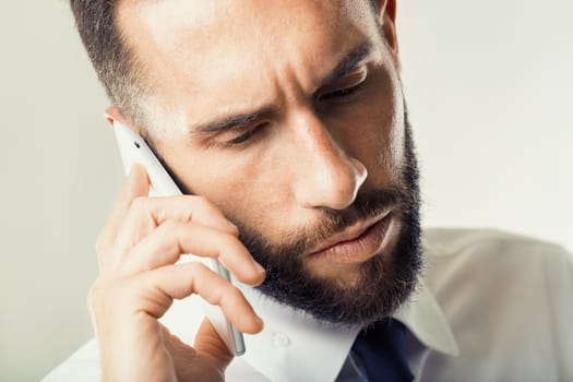 Man in business attire handles a tense call, his intense gaze reflecting the gravity of the conversation