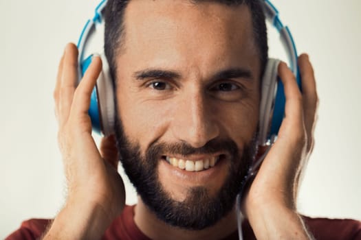 Beaming man engaging with music via blue headphones exudes happiness