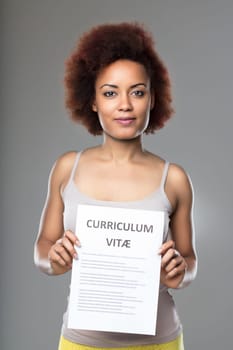 Woman holding her resume with a hopeful expression, anticipating career advancement