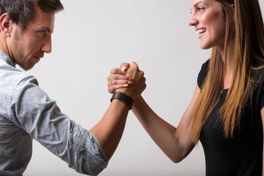 A man and woman face off in playful defiance, challenging each other to an arm wrestle. Symbolizing male versus female, both as friends, lovers, and rivals, they maintain a sense of pride and fun whil