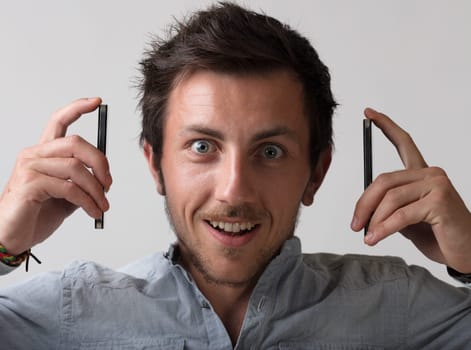 ridiculous and symbolic image of young man between two smartphones, too busy with calls to do anything else. How stressful!
