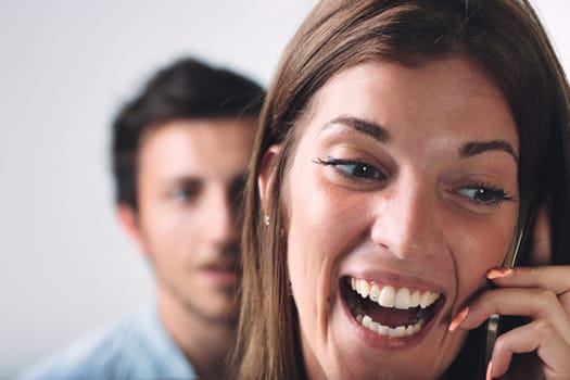 A woman on a phone call takes the foreground, with a blurred, suspicious young man in the backdrop. It insinuates betrayal, jealousy, love, stormy relations - the notion of a man's jealousy, frustrati