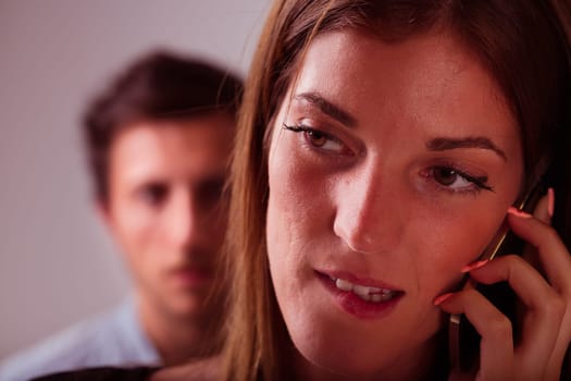 A woman on a phone call takes the foreground, with a blurred, suspicious young man in the backdrop. It insinuates betrayal, jealousy, love, stormy relations - the notion of a man's jealousy, frustrati