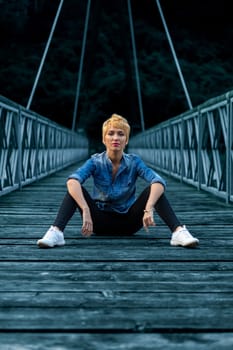 Surrounded by natures splendor, her relaxed pose on the bridge contrasts the wild river below