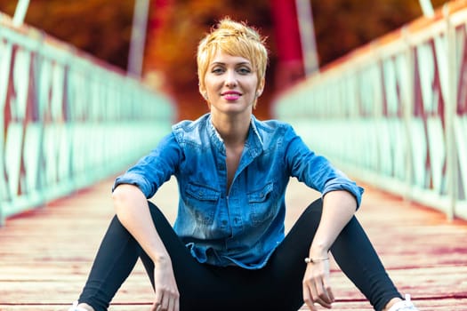 Her denim merges with the natural palette of the mountains, exuding serene confidence on the bridge