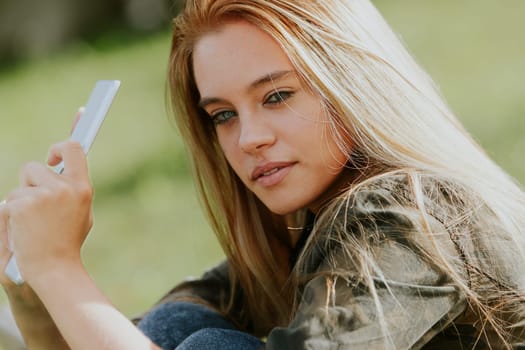 Digital era leisure: young woman with tablet enjoys time on a park bench
