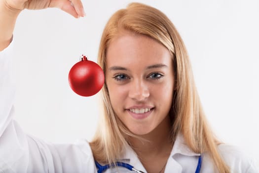 Concept of donations and charity related to the holiday season and medical or healthcare environment blurred young woman in the background, hands in focus, with a red Christmas decoration in front of