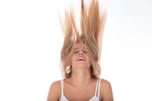 Full of life, young woman with hair tossed high laughs against a bright background