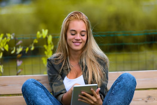 Generation Z girl entertains and informs herself using the mobile internet is outdoors in nature