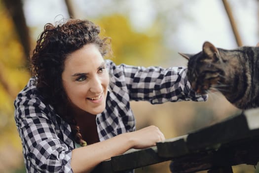 Portrait of feline with human. Portrait of woman with cat. In the woods a woman and a cat meet and caresses are bestowed. Who enjoys it more? Let's find out.