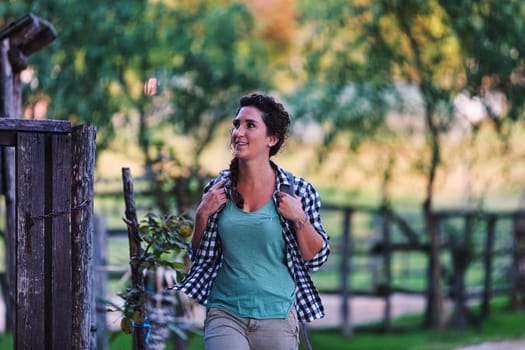 Young travel blogger and video influencer is being a tourist at the expense of followers by showing the beauty of the forest and nature she visits. She is wearing backpack and plaid shirt.