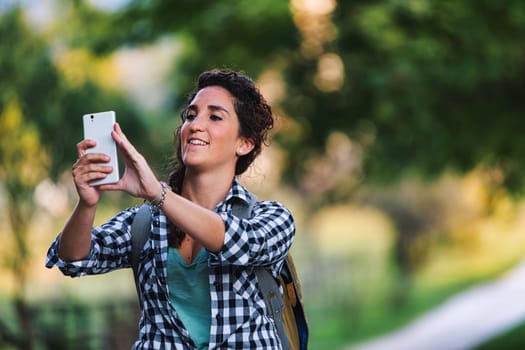 Woman takes pictures with her smartphone of everything she sees in the countryside. A woman with braids is on a nature trip. she is a tourist in the middle of the woods and nature.