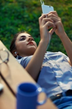 Young woman outdoors uses smartphone for fun, self-promotion, influencer marketing, content creation, video production, and selfies. Engaged in social media, she produces highly consumable content, em