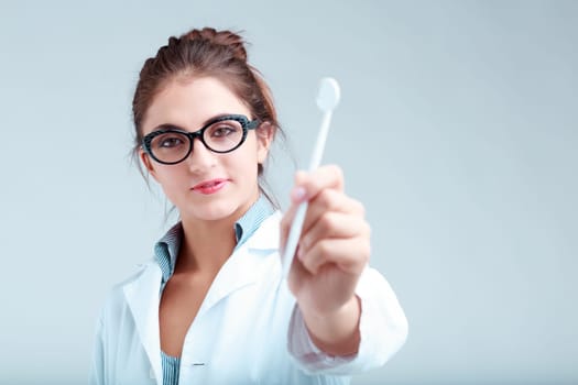dentist in soft focus displays dental tool, stressing the importance of mechanical action for oral health and fresh breath