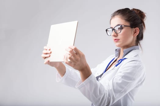 A woman wearing a white lab coat carefully scrutinizes the data on the digital tablet held at eye level, as if it were an x-ray film. It doesn't make any sense, but it evokes the concept for those who
