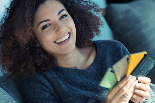 Beautiful curly-haired woman, showcasing perfect teeth and ethnic looks, selects colors from swatches for home decor, intensely absorbed and excited to express her aesthetic preference in her lifestyl