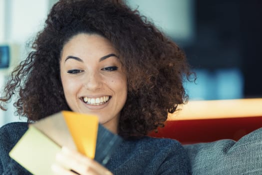 Ethnic-looking, stunning woman with perfect teeth, enthusiastically chooses color samples on her couch, excited about personalizing her lifestyle. She's intensely focused on her home decor