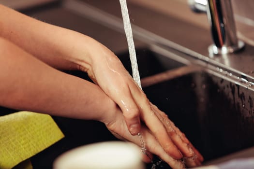 Female hands under water from a kitchen faucet. A privilege to have clean, potable water at home, some appreciate and pay taxes for it