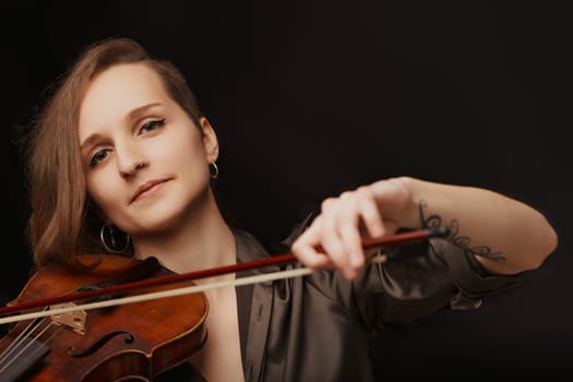 Elegance and skill merge as a woman plays the violin, her expression soft with musical fervor