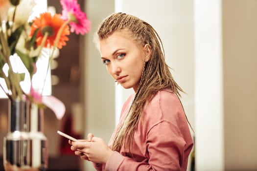 Enjoying digital content on her phone, a girl with box-braid braids in a pink hoodie is the new face of entertainment