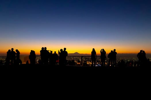 Silhouettes of people against a vibrant sunset , fuji mountain on background
