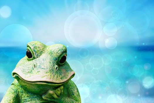 Frog background. Decorative old weathered ceramic frog figure over abstract blue turquoise ocean. Beautiful backdrop for summer holidays and travel advertising.