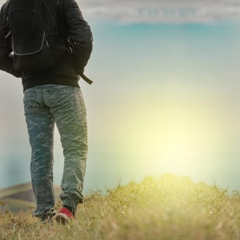 Backpacker man walking in field back view, close up of man from behind in field, low angle of backpacking man with copy space