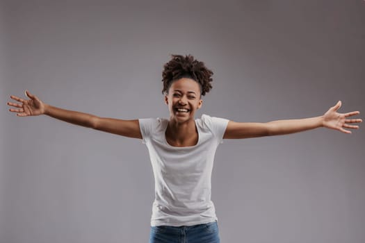 Bright-eyed young woman offers a welcoming gesture, her attire suggesting comfort and simplicity