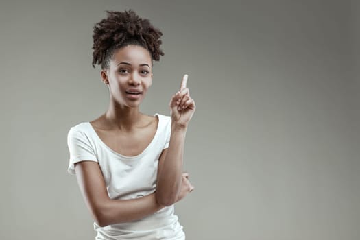 Thoughtful young Black woman gestures an idea, poised in a white tee