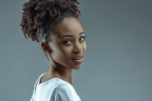 Young Black female turns shoulder, smiles back with eyes full of mirth