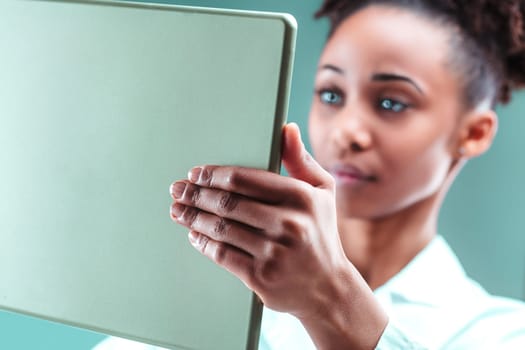 With meticulous attention, a woman in a white coat studies details on her tablet screen