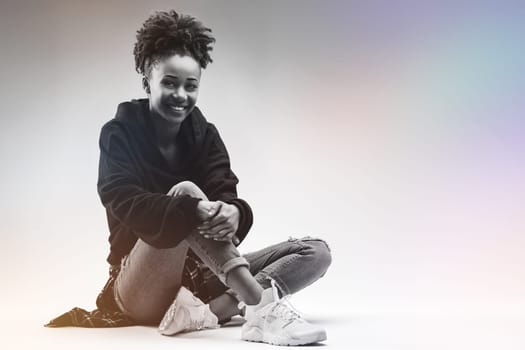Casual and content young woman sits cross-legged, smiling gently