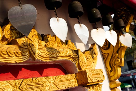 A row of bells hanging from a building. The bells are hanging from a wooden roof structure.