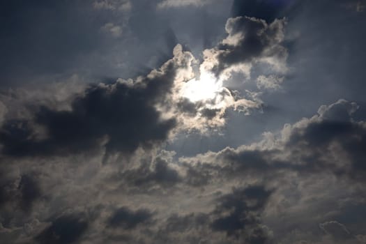Cloudscape of sky with heavy rain backdrop. The bright sun behind the thick clouds