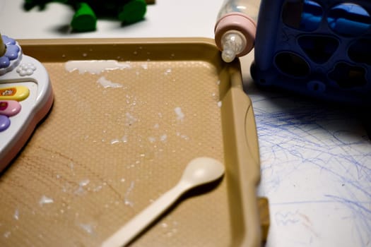Milk is pouring out of a bottle a child's dining table