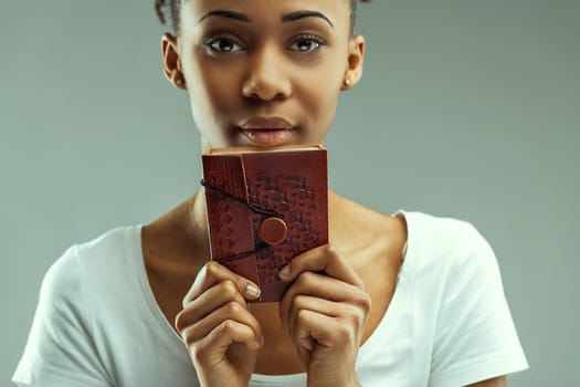 Eyes full of stories, a young woman gazes over a vintage red book, mystery abounds