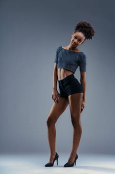 Trendy young woman models a crop top and shorts with sparkling heels